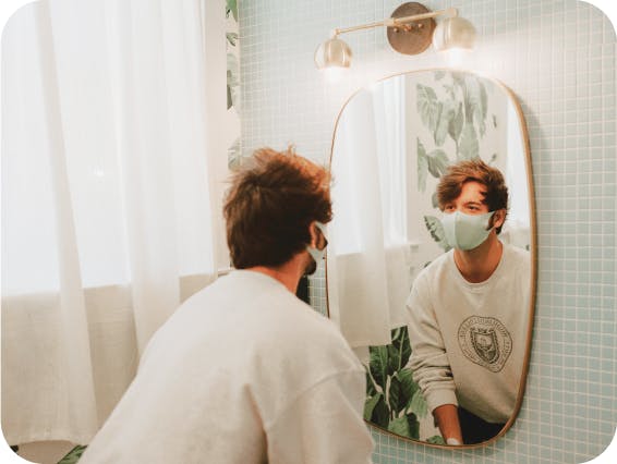Man wearing a mask and looking in the mirror